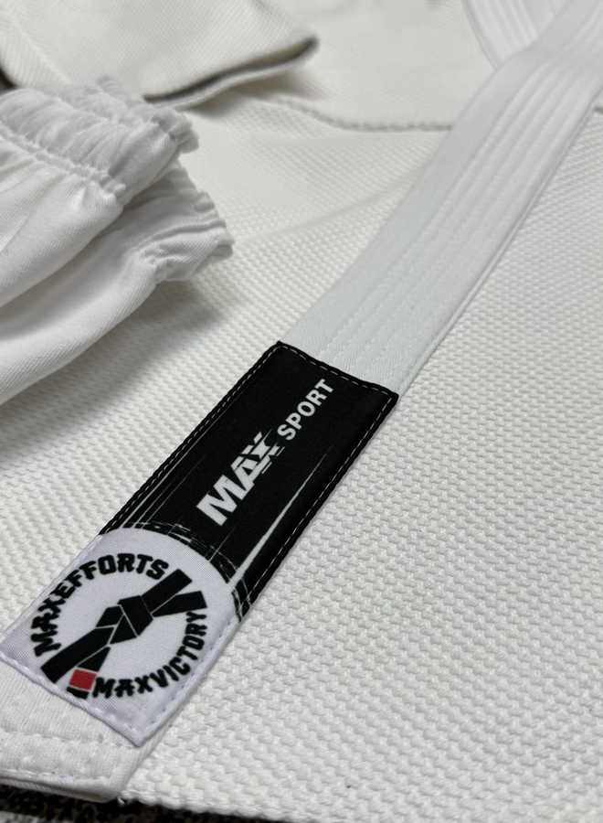 Крупний план білого кімоно MAX SPORT з чорною брендованою етикеткою на комірі та складеними штанами поруч.